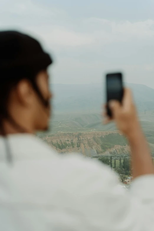 a person taking a picture with a cell phone, inspired by Zhang Kechun, trending on unsplash, happening, hills in the background, turkey, zoomed out portrait of a duke, taken in the late 2010s