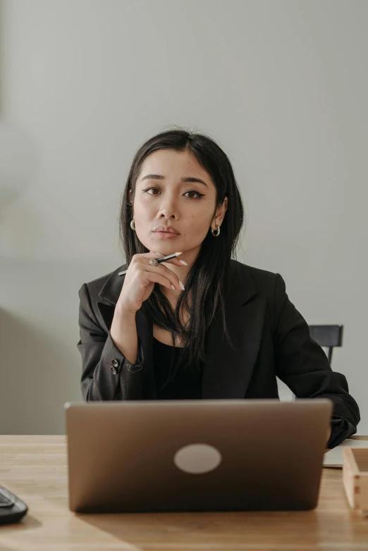 a woman sitting in front of a laptop computer, inspired by Li Di, trending on pexels, realism, wearing a black noble suit, looking serious, asian human, instagram post