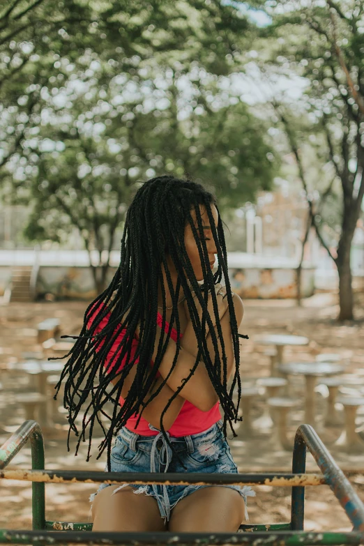 a woman with dreadlocks sitting on a bench, pexels contest winner, standing with her back to us, deep black roots, with textured hair and skin, having fun. vibrant