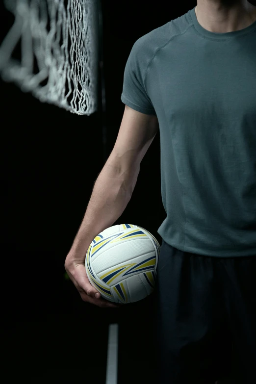 a man holding a soccer ball in front of a net, in front of a black background, upper body image, promotional image, volleyball