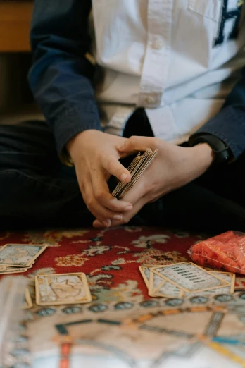 a man sitting on the floor playing a game of cards, by Julia Pishtar, pexels contest winner, instagram story, bags of money, tarot swords, 15081959 21121991 01012000 4k