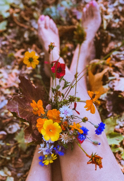 a person laying on the ground with a bunch of flowers, an album cover, inspired by Elsa Bleda, unsplash, land art, closeup of arms, seasons!! : 🌸 ☀ 🍂 ❄, colorful wildflowers, cottagecore hippie