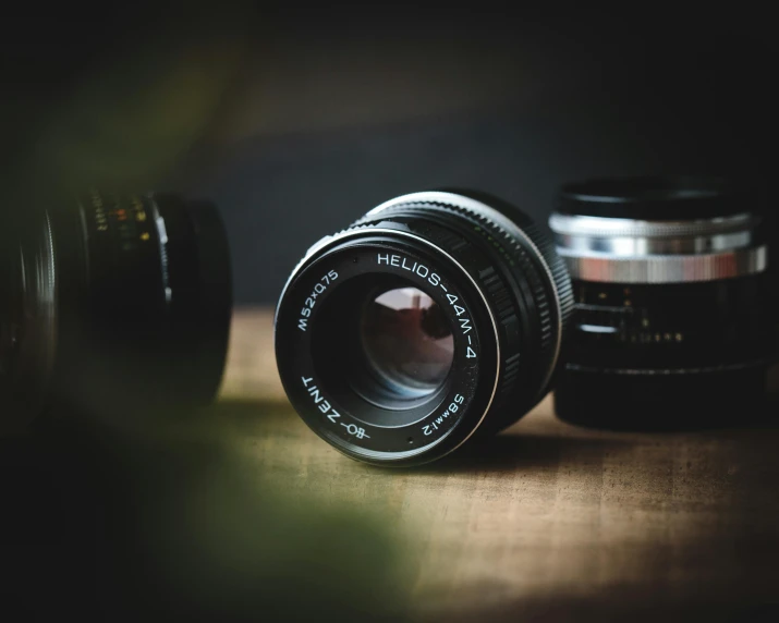 a camera lens sitting on top of a wooden table, by Niko Henrichon, pexels contest winner, photorealism, rolleiflex, optical lenses, looking at camera, medium format