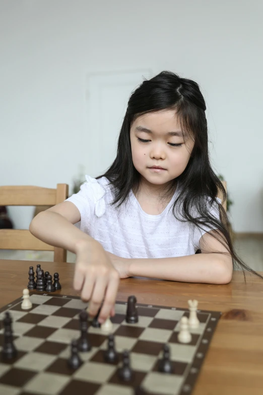 a little girl sitting at a table playing chess, pexels contest winner, square, asian female, smooth feature, annoyed