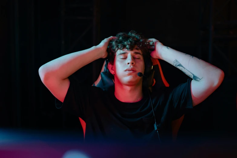 a close up of a person with headphones on, inspired by John Luke, trending on pexels, menacing pose, server in the middle, looking exhausted, sitting down