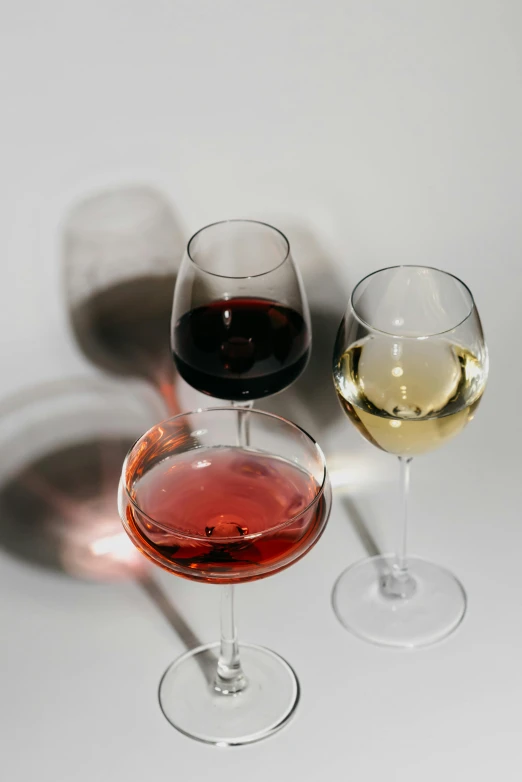 three glasses of wine sitting next to each other, by Carey Morris, pexels, on a pale background, red white and black, mead, sydney hanson