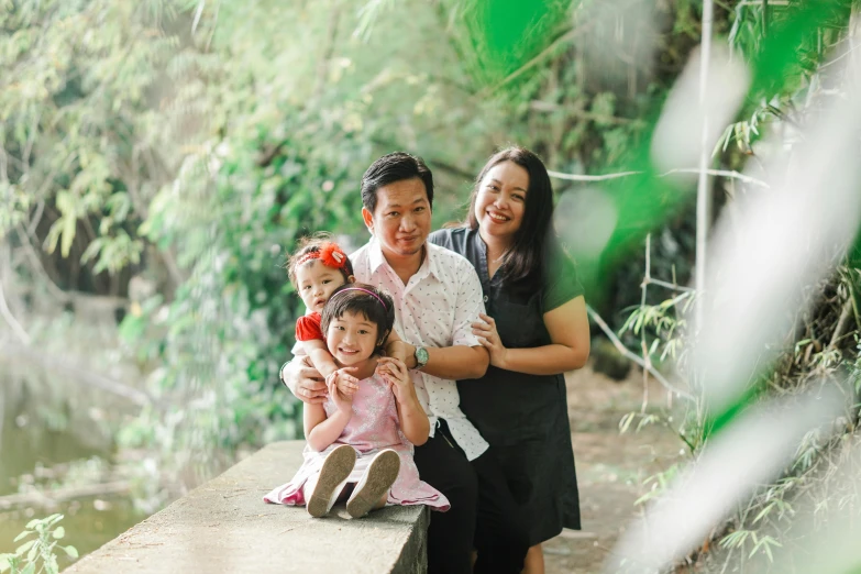 a family poses for a picture on a bridge, pexels contest winner, realism, amongst foliage, manila, portrait image, portrait n - 9