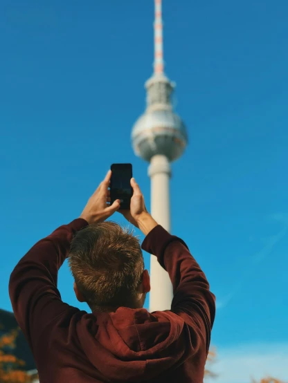 a man taking a picture of the television tower, a photo, pexels contest winner, berlin secession, short hair on top of his head, 🚿🗝📝