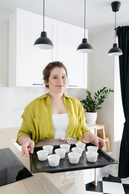 a woman holding a tray with cups on it, profile image, for displaying recipes, looking towards camera, dasha taran