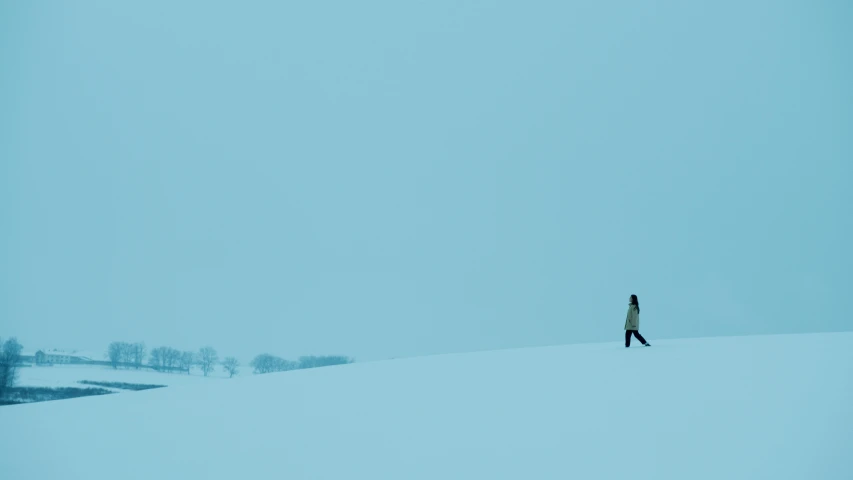 a person walking across a snow covered field, by Maciej Kuciara, minimalism, blue, shot on hasselblad, **cinematic, on a hill