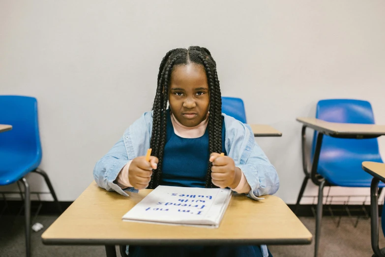 a young girl sitting at a desk in a classroom, pexels contest winner, realism, subject action : holding sign, african american young woman, silly and serious, high quality photo