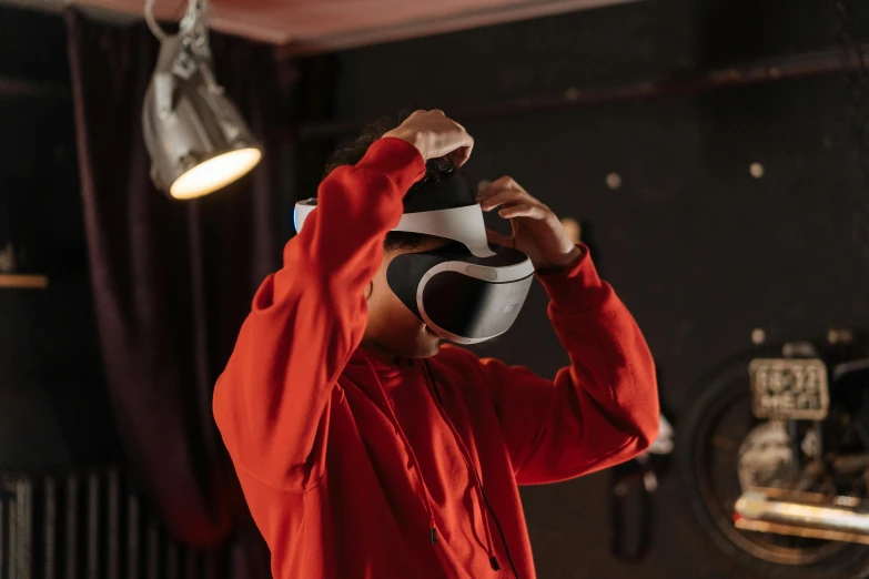 a man in a red shirt holding a helmet over his head, trending on pexels, interactive art, 3 d goggles, white man with black fabric mask, taken with sony alpha 9, doing a sassy pose