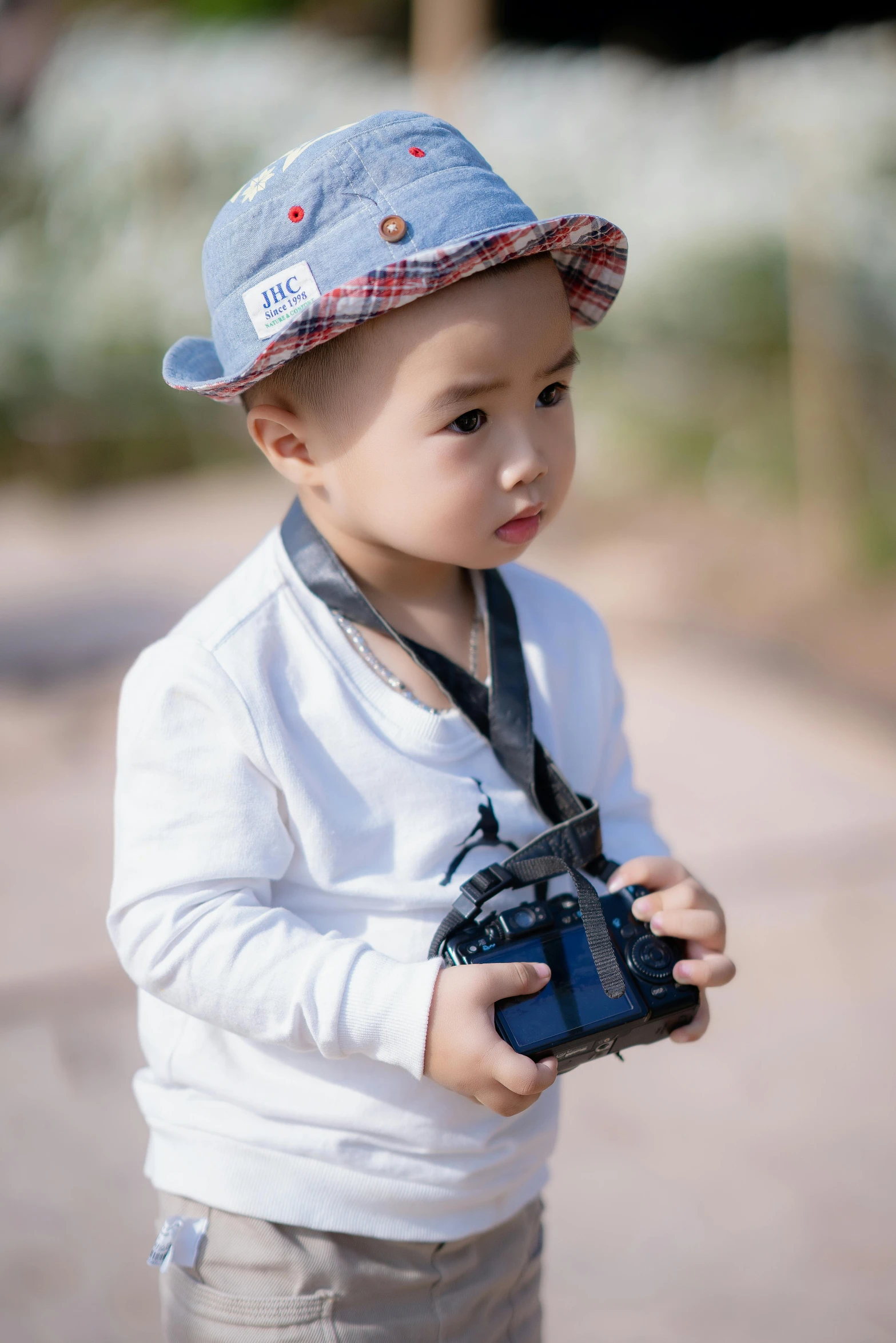 a little boy that is holding a camera, wearing a navy blue utility cap, darren quach, wearing a light grey crown, multicoloured