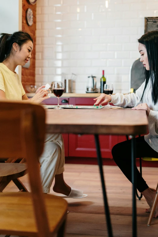 two women sitting at a table in a kitchen, pexels contest winner, pair of keycards on table, asian female, romance, square