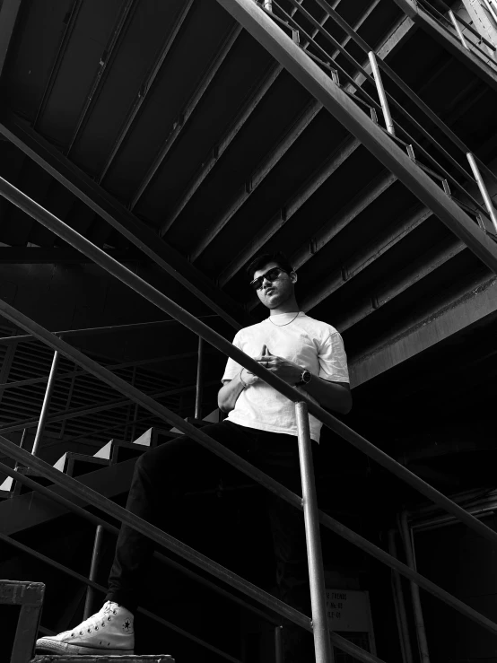 a man standing on a set of stairs next to a fire hydrant, a black and white photo, by Adam Rex, with sunglass, yung lean, shot on iphone, in a warehouse