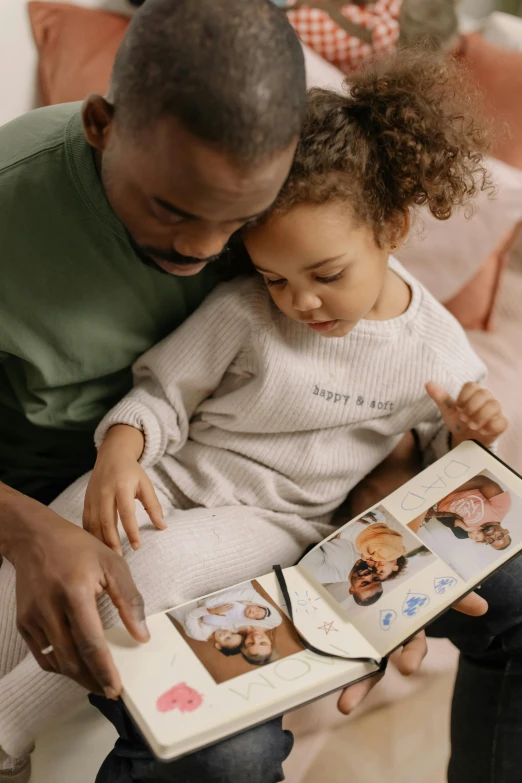 a man reading a book to a little girl, a picture, pexels contest winner, scrapbook, babies in her lap, brown, gif