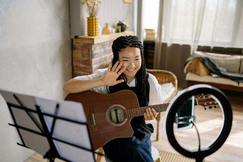 a woman sitting in front of a mirror playing a guitar, trending on pexels, chinese woman, while smiling for a photograph, girl wearing headphones, in a studio hollow