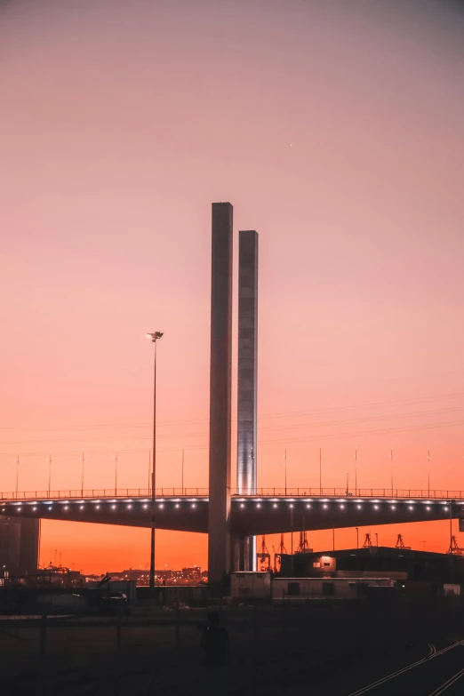 a bridge over a body of water at sunset, by Jens Søndergaard, pexels contest winner, modernism, tall towers, highway, melbourne, 🚿🗝📝