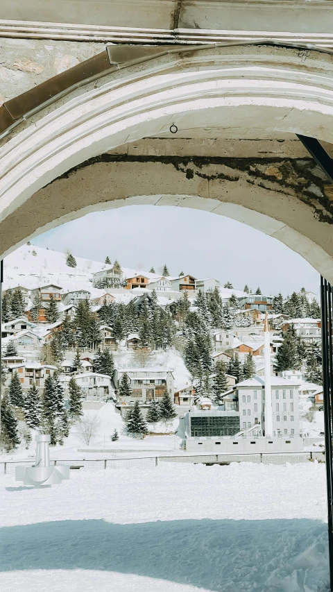 a man riding a snowboard down the side of a snow covered slope, by Tobias Stimmer, pexels contest winner, art nouveau, arched doorway, view of villages, white pale concrete city, julia hetta