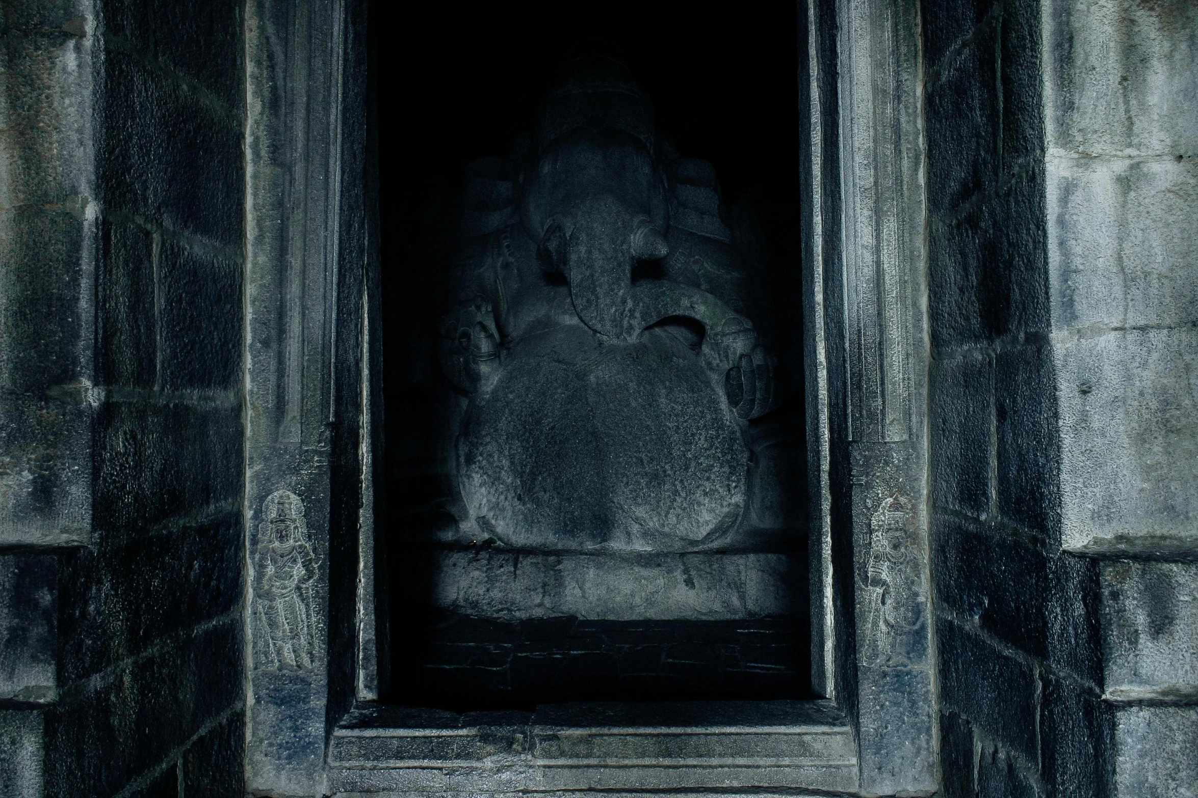 a stone statue in a doorway of a building, by Elsa Bleda, pexels contest winner, ganesha, dark eerie movie frame, rectangle, grey