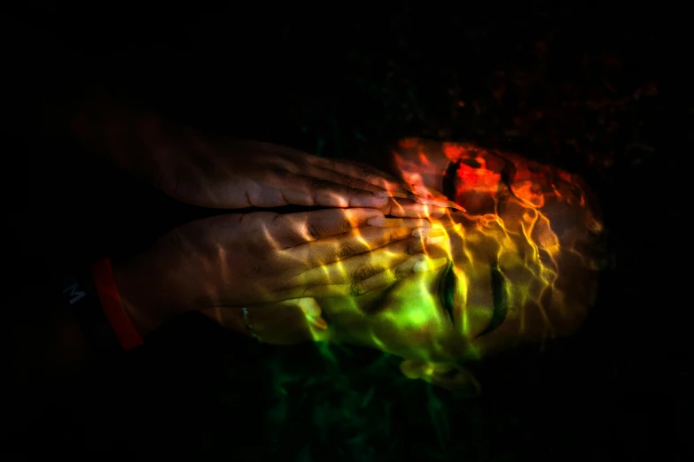 a close up of a person's hands in the dark, by Jan Rustem, pexels contest winner, holography, face submerged in colorful oils, backlit face, lying on an abstract, green and red tones