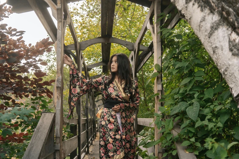 a woman in a floral dress standing on a bridge, inspired by Itō Shinsui, unsplash, wearing a velvet robe, in a tree house, portrait image, gothic clothing