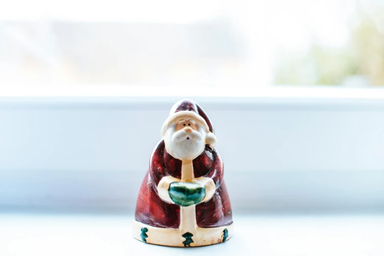 a close up of a santa figurine on a window sill, inspired by Ernest William Christmas, unsplash, folk art, on a candle holder, medium wide front shot, set against a white background, made of glazed