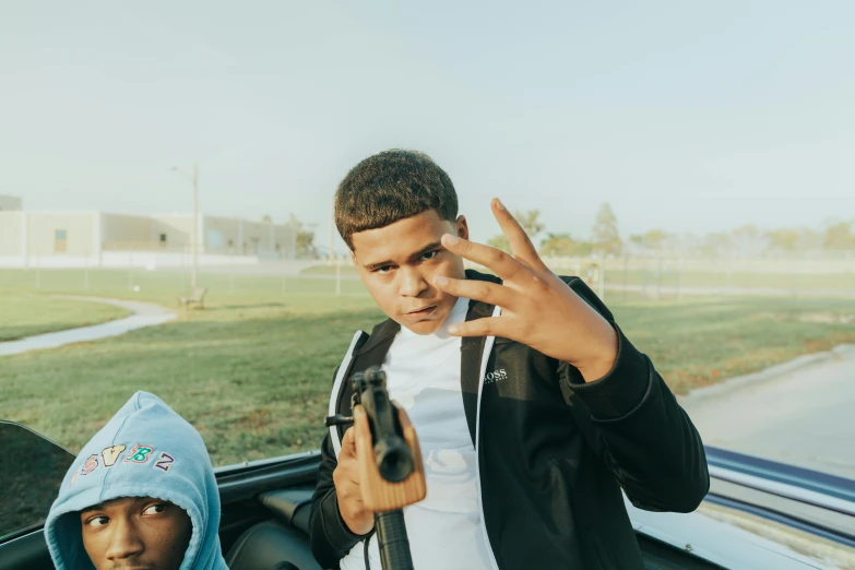two young men standing next to each other in a car, by Carey Morris, trending on pexels, realism, holding handgun, yung lean, black teenage boy, 8k octan photo