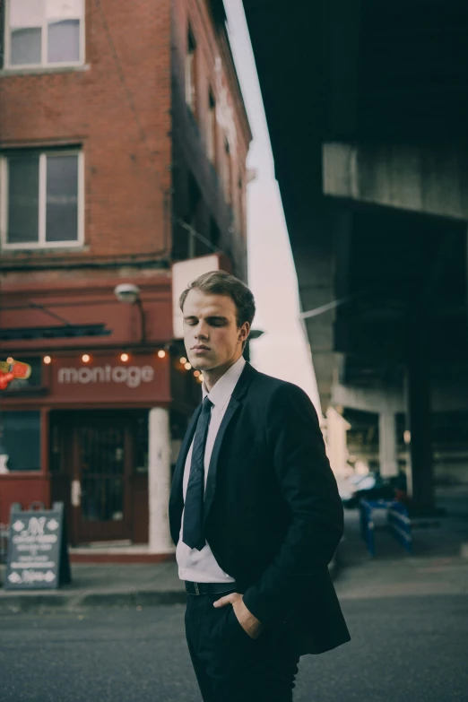 a man in a suit standing in the middle of a street, an album cover, by Jacob Toorenvliet, looking to the side off camera, wearing causal black suits, paul davey, sydney hanson