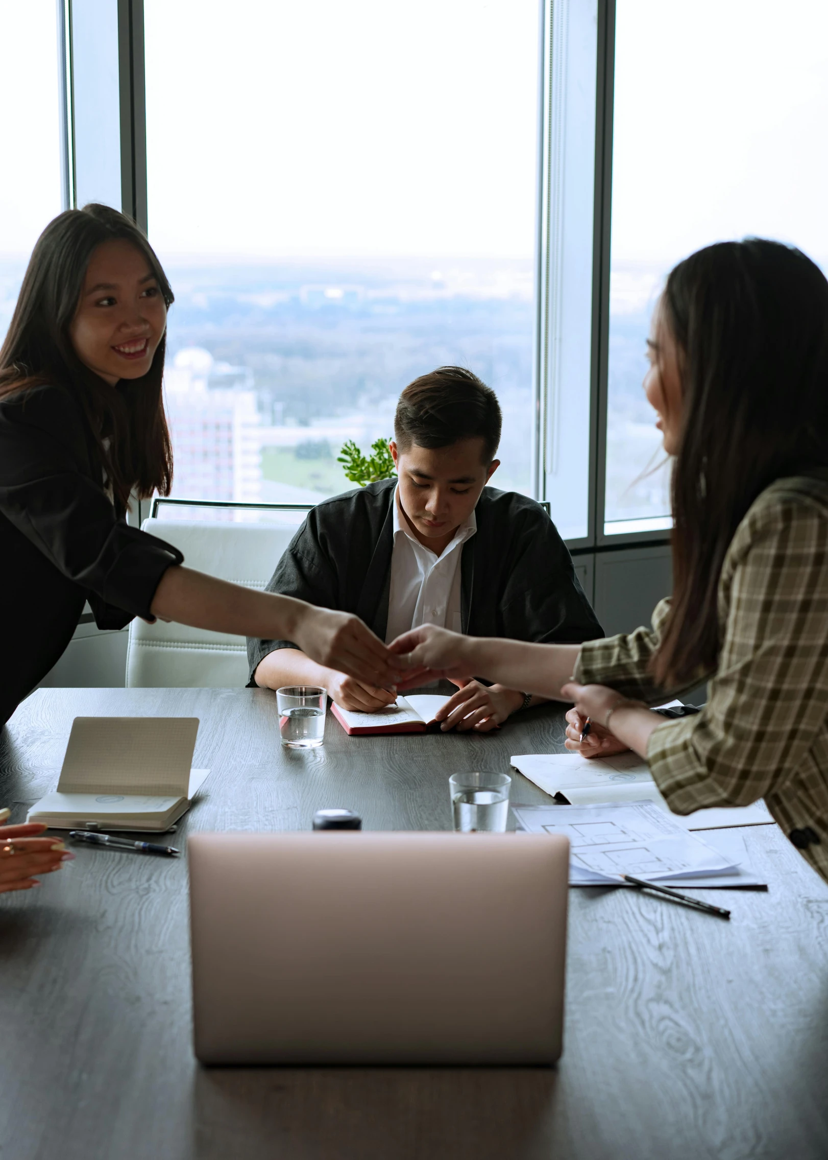 a group of people sitting around a wooden table, on a desk, reaching out to each other, thumbnail, asian women