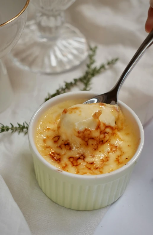 a close up of a bowl of food with a spoon, flan, ivory, passion, square