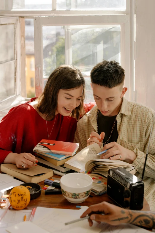 a couple of people that are sitting at a table, trending on pexels, academic art, holding books, lesbians, declan mckenna, happy couple