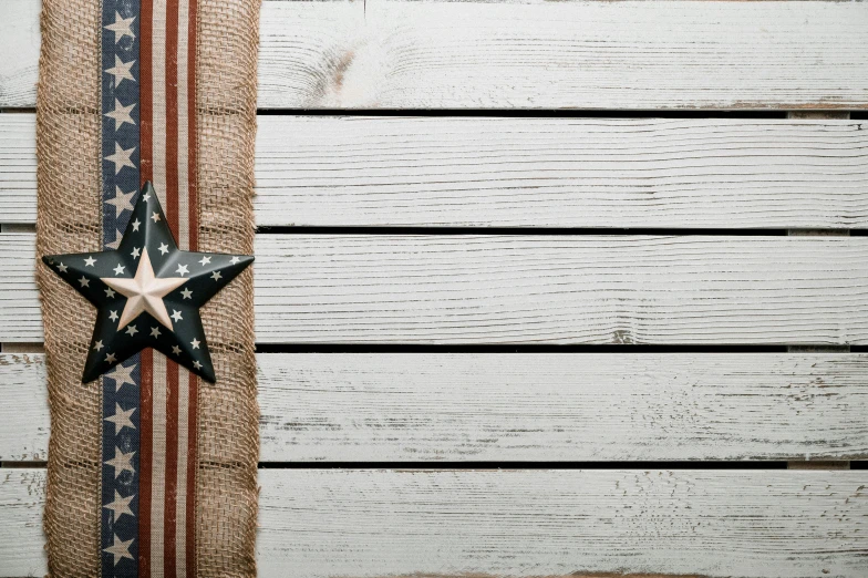 a patriotic star sitting on top of a piece of burlock, pexels contest winner, american realism, white plank siding, hessian cloth, background image, lying scattered across an empty