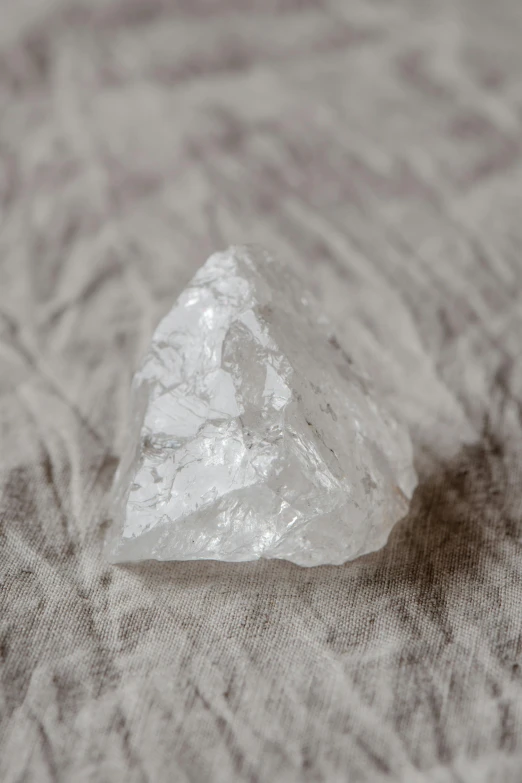 a white diamond sitting on top of a table, by Helen Biggar, unsplash, calcite, soft scale texture, pointed face, transparent cloth