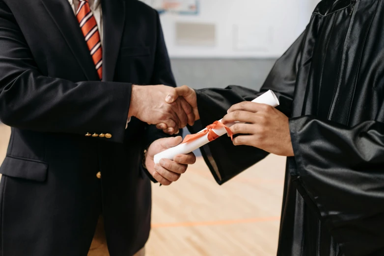 a man shaking another man's hand at a graduation ceremony, pexels contest winner, hand holding cap brim, inspect in inventory image, embroidered robes, advertising photo