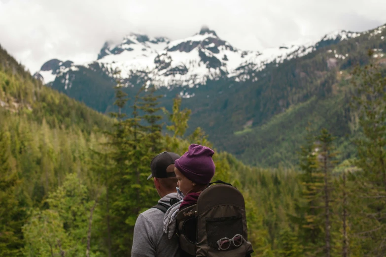 a couple of people that are standing in the grass, by Hazel Armour, pexels contest winner, solo hiking in mountains trees, father with child, pacific northwest coast, avatar image