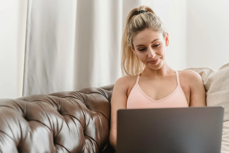 a woman sitting on a couch using a laptop, trending on pexels, wearing bra, a girl with blonde hair, brunette woman, mid 2 0's female