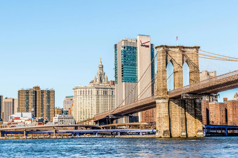 a bridge over a body of water with a city in the background, pexels contest winner, hudson river school, frank gehry, new york buildings, clear and sunny, conde nast traveler photo
