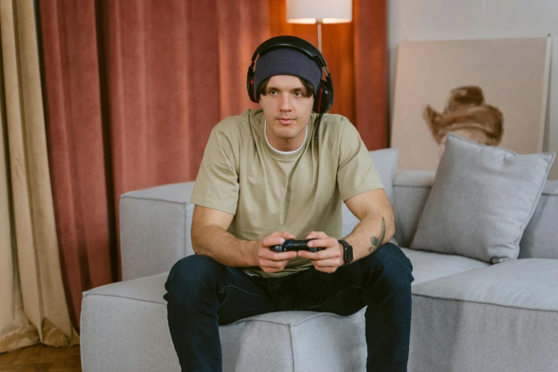 a man sitting on a couch playing a video game, inspired by Niko Henrichon, pexels, hyperrealism, headphones on head, joe keery, australian, casually dressed