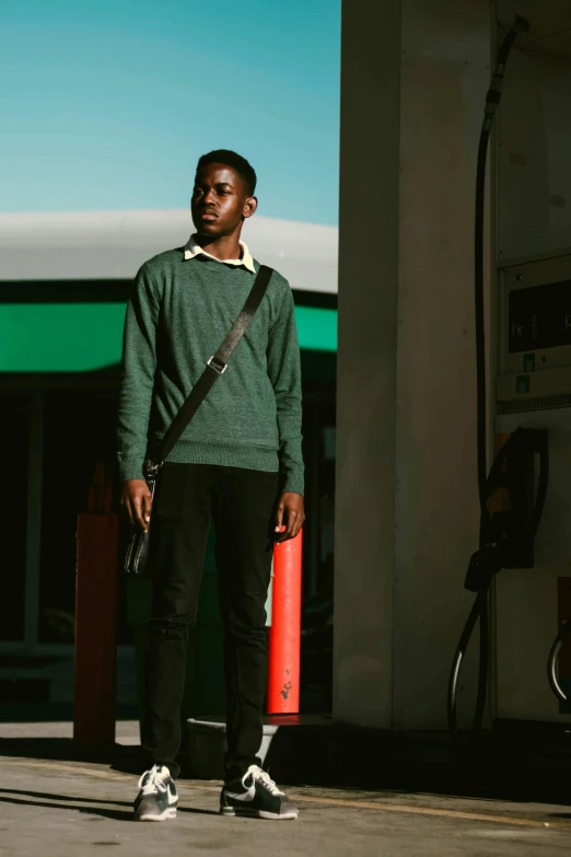 a man standing in front of a gas station, pexels contest winner, renaissance, wearing a green sweater, mkbhd, ignant, modeling