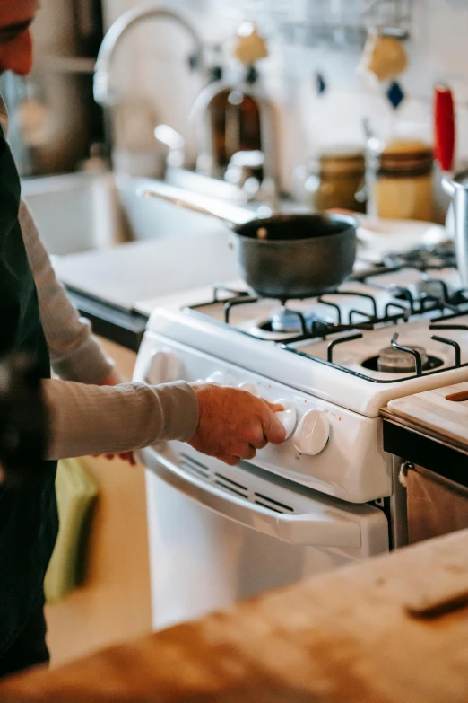 a man that is standing in front of a stove, by Elizabeth Durack, pexels contest winner, hands on counter, white, walking down, easy to use