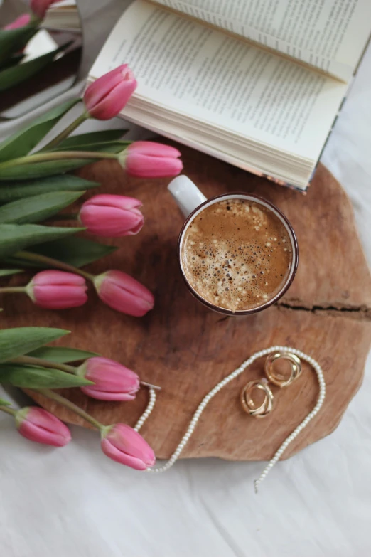 a cup of coffee next to a bunch of pink tulips, by Lucia Peka, trending on pexels, romanticism, wooden jewerly, storybook style, wood and gold details, coffee stain