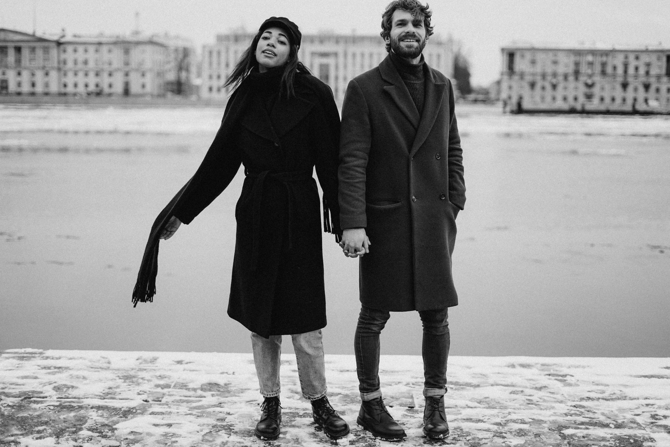 a man and a woman standing next to each other, a black and white photo, by Kristian Zahrtmann, pexels, antipodeans, only snow in the background, mucha and artem demura, standing on the water ground, on the sidewalk