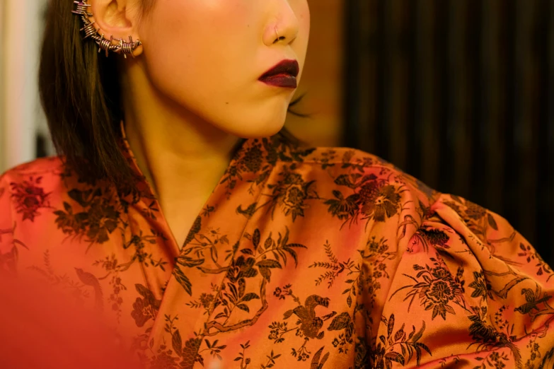 a close up of a person holding a cell phone, an album cover, inspired by Xia Chang, trending on pexels, ukiyo-e, cheongsam, wearing a luxurious velvet robe, orange and black tones, portrait image