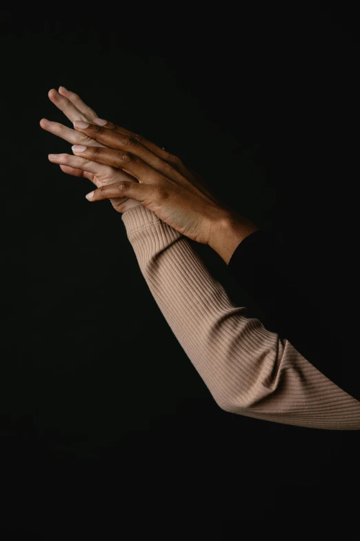 a woman holding her hands up in the air, by Nina Hamnett, trending on unsplash, renaissance, on black background, white sleeves, dark and beige atmosphere, in style of robert mapplethorpe