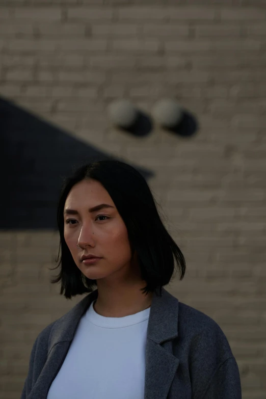 a woman standing in front of a brick building, inspired by Kim Tschang Yeul, unsplash, realism, androgynous male, grey backdrop, headshot profile picture, streetwear