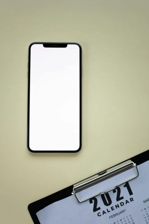 a cell phone sitting on top of a desk next to a calendar, by Sven Erixson, trending on pexels, minimalism, mirror and glass surfaces, tall thin frame, no - text no - logo, square
