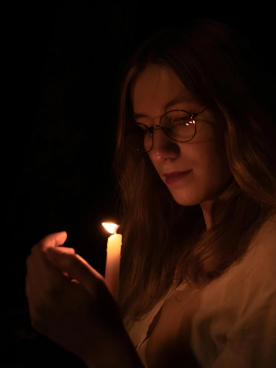 a woman holding a lit candle in her hand, a portrait, inspired by Elsa Bleda, pexels, concert photo, instagram post, ignant, profile image