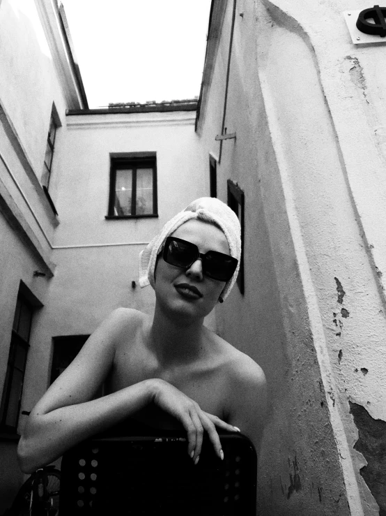 a black and white photo of a woman with a towel on her head, inspired by Helmut Newton, in front of the house, 🤤 girl portrait, young handsome pale roma, wearing shades