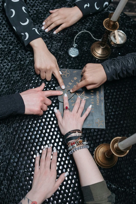 a group of people that are sitting around a table, an album cover, by Julia Pishtar, trending on pexels, renaissance, black hands with black claws, occult symbols and diamonds, tourist photo, runic rings